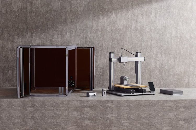 Kompakt maskin för hemmagym med en genomskinlig skyddslåda på en grå bakgrund.